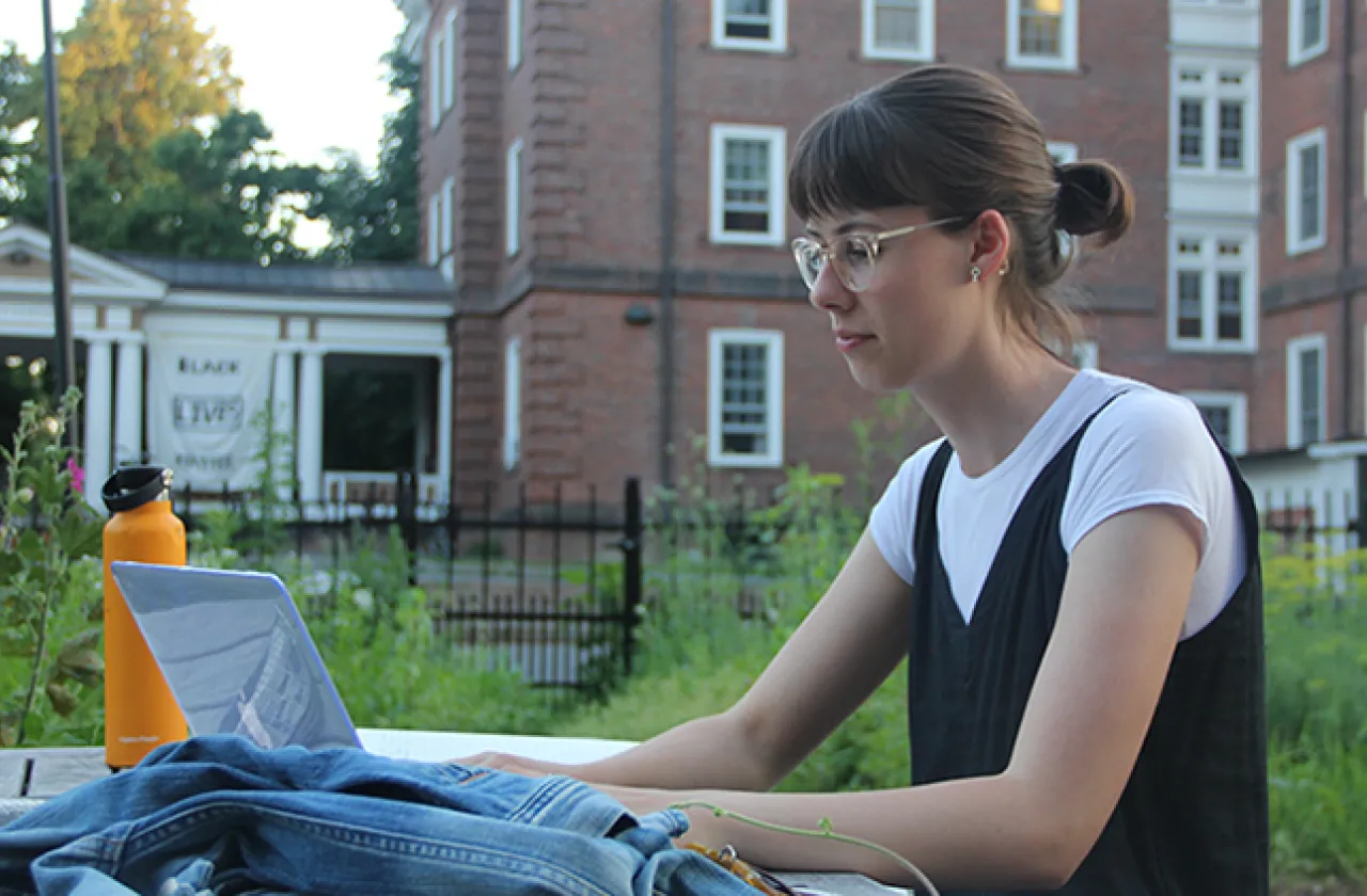 Student sitting outside working on a laptop