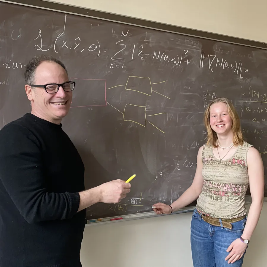 Luca Capogna and Abi Bowering ’24 stand in front of a chalkboard with equations on it.