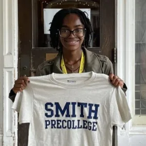 A precollege student holding up a Smith shirt.