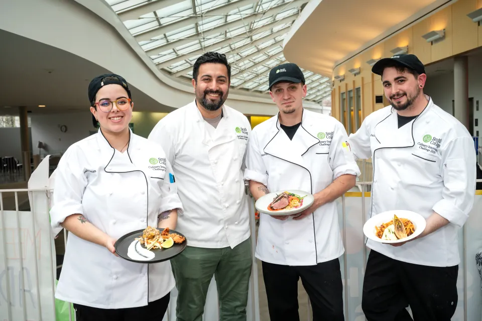 Four Smith chefs hold plates of food.