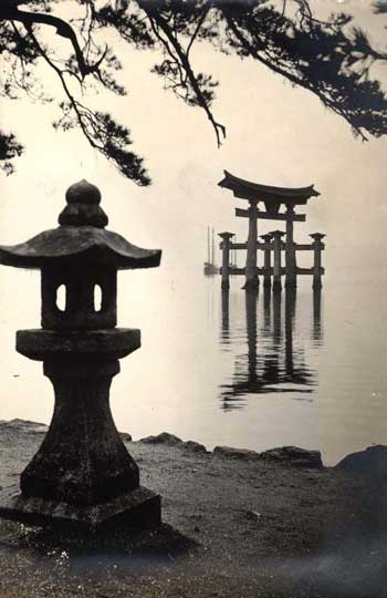 Itsukushima, Japan: Another view of the great red Torii at Miyajima, this time from the shore, showing a couple of fishing boats anchored off it.