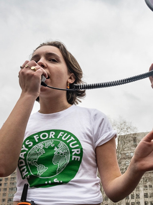 Amina Rose Castronova speaking into a loudspeaker, wearing a Fridays for Future tshirt