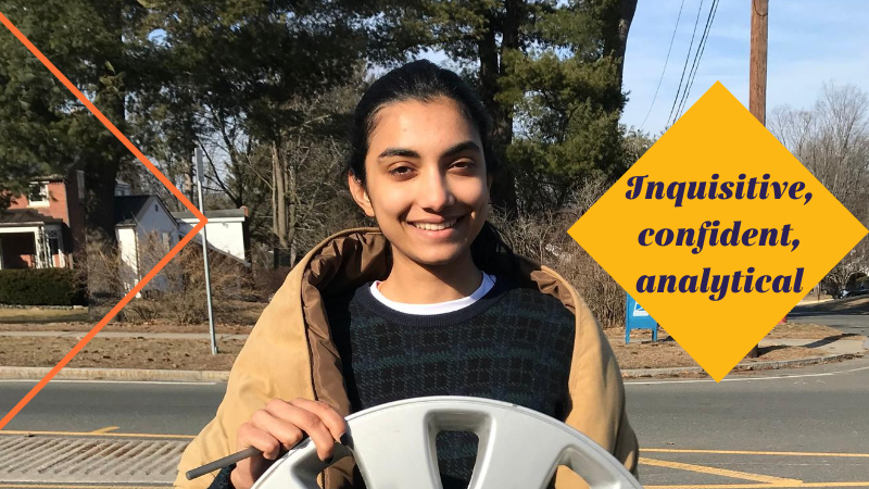 Amrita holding a hubcap with words "Inquisitive, confident, analytical" overlaid