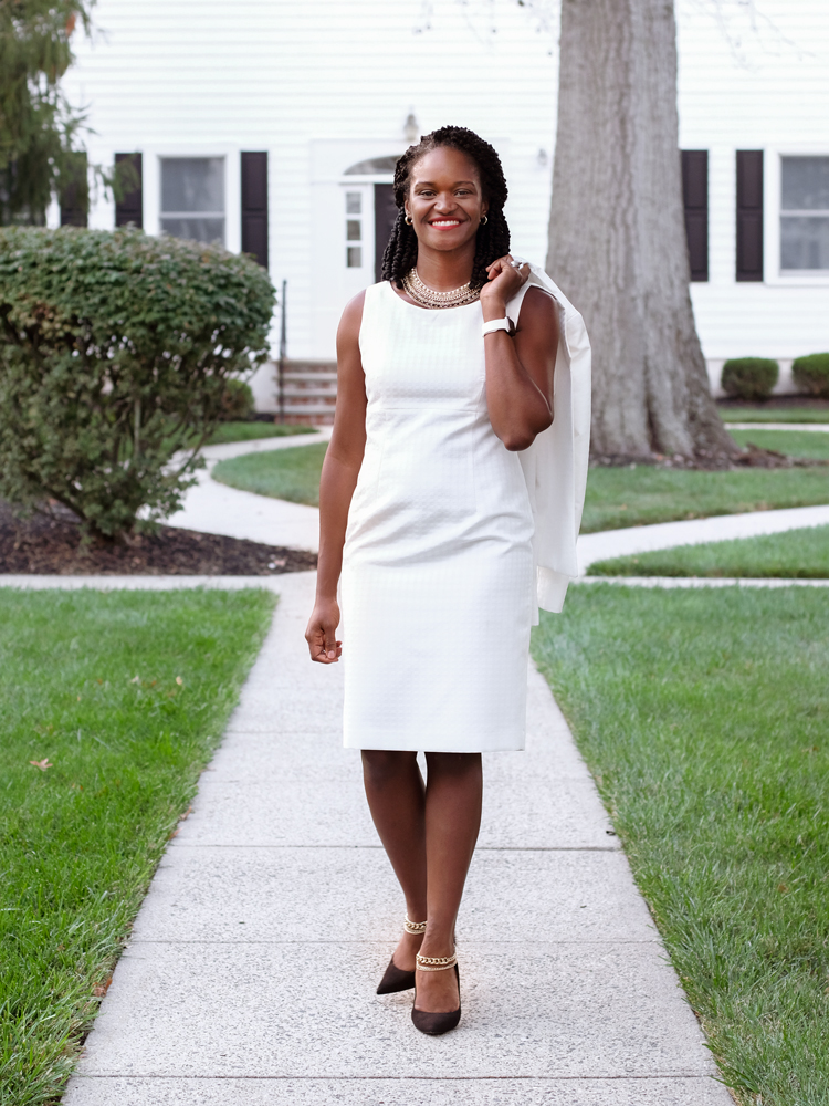 KaNeda Bullock in a white dress on the path in front of a suburban colonial house