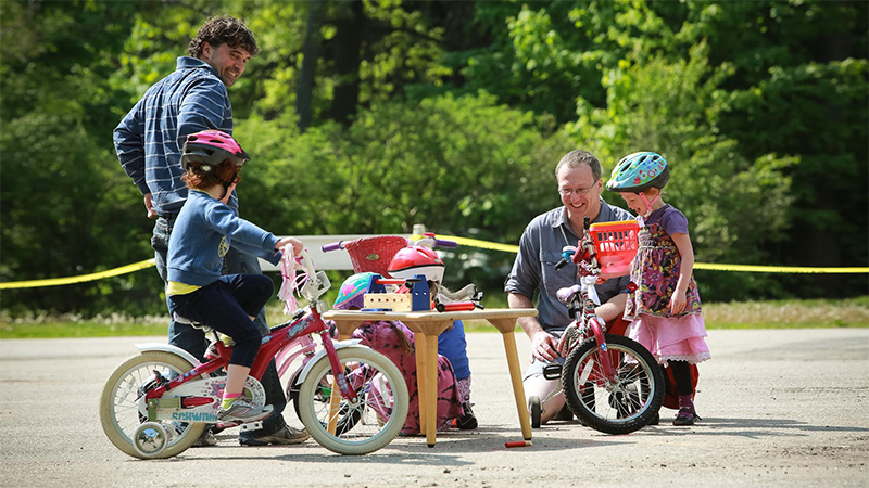 Two fathers with small children on bikes