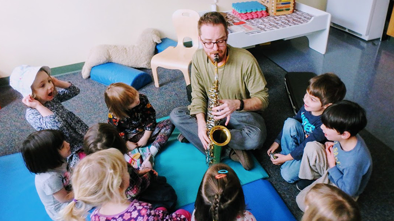 Teacher demonstrating a saxophone to a group of children