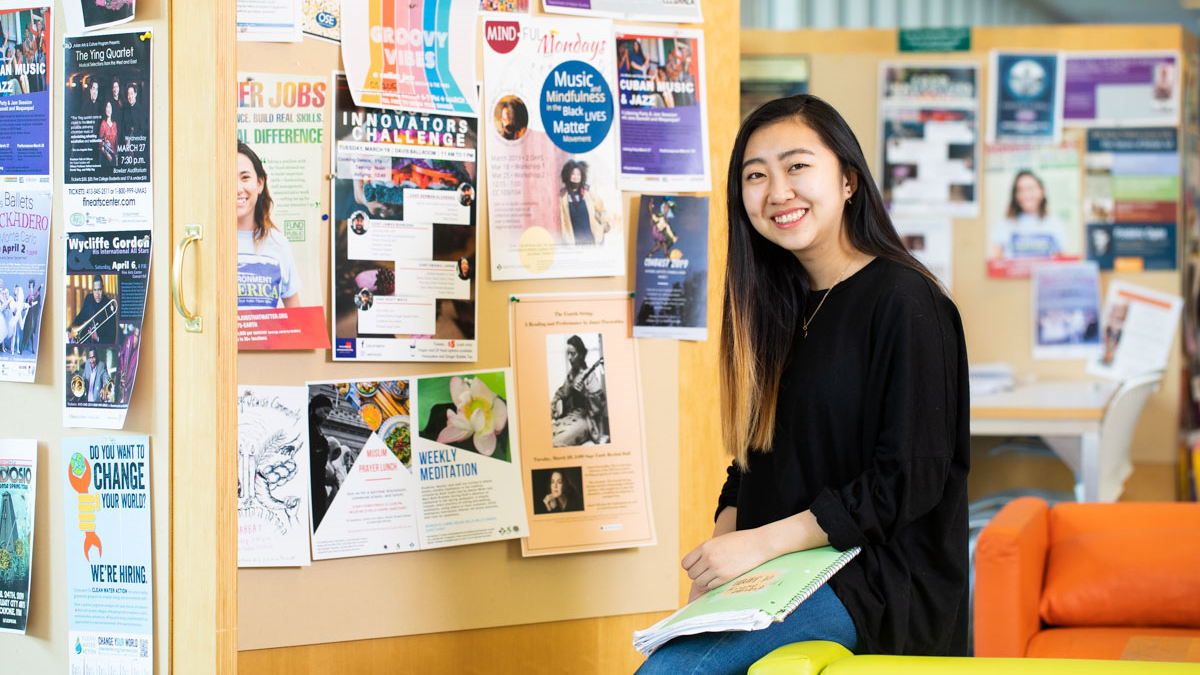 Student in front of a bulletin board covered with posters