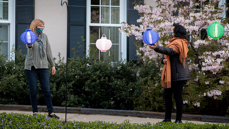 President McCartney and Denise Materre putting lanterns in front of Alumnae House for Global Illumination