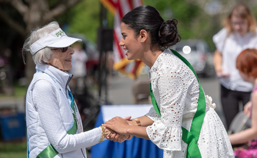 An elderly alum and a young alum shake hands with joy