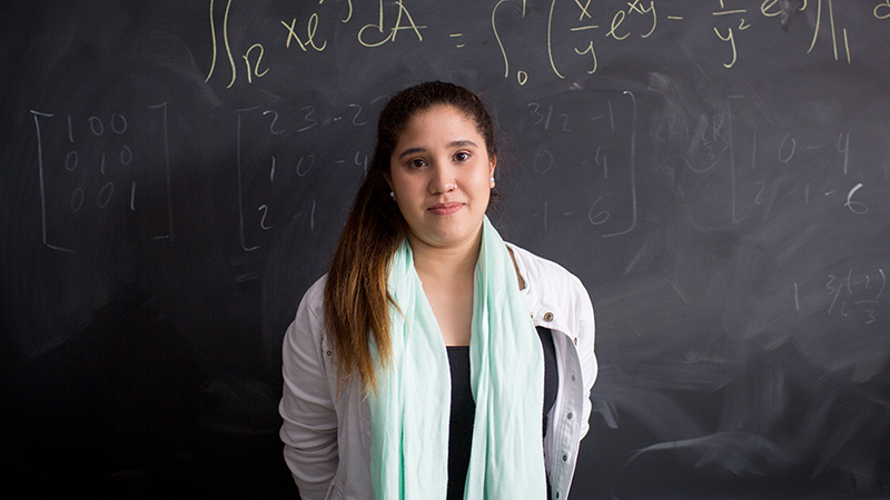 Dana Vera in front of a classroom blackboard