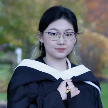 Demi Gong ’24 dressed in black graduation robes with a 2024 tassel