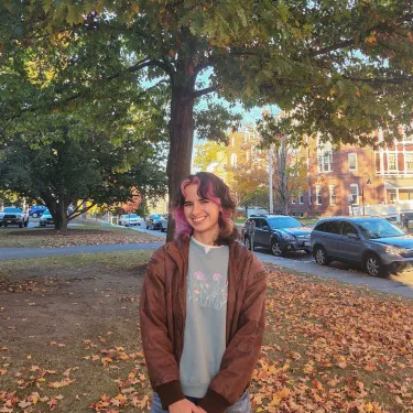 Profile photo of Ciana Socias standing outside in the fall with orange leaves behind her