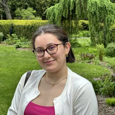 Nermine Mokdad profile photo, standing outside amidst greenery, smiling