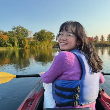 Sherry Li, in a kayak in the fall, looks over her shoulder, smiling