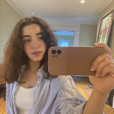 Karen Bekhazi holding a phone and taking a selfie in a mirror