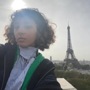 Maya Delmont poses in front of the Eiffel Tower on a sunny day