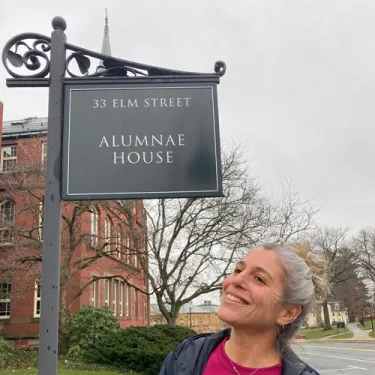 Amy Altwarg looking up at the Smith College Alumnae House sign