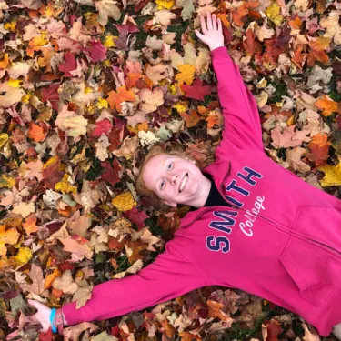 Maddie Wettach laying in autumn leaves.