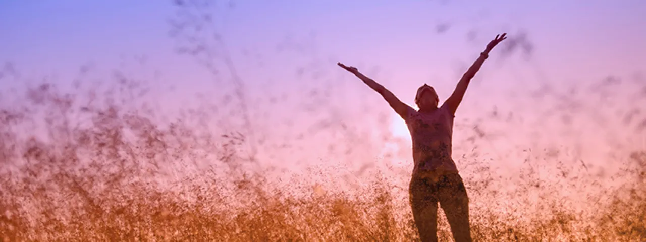 Silhouetted photo of a person throwing their arms in the air