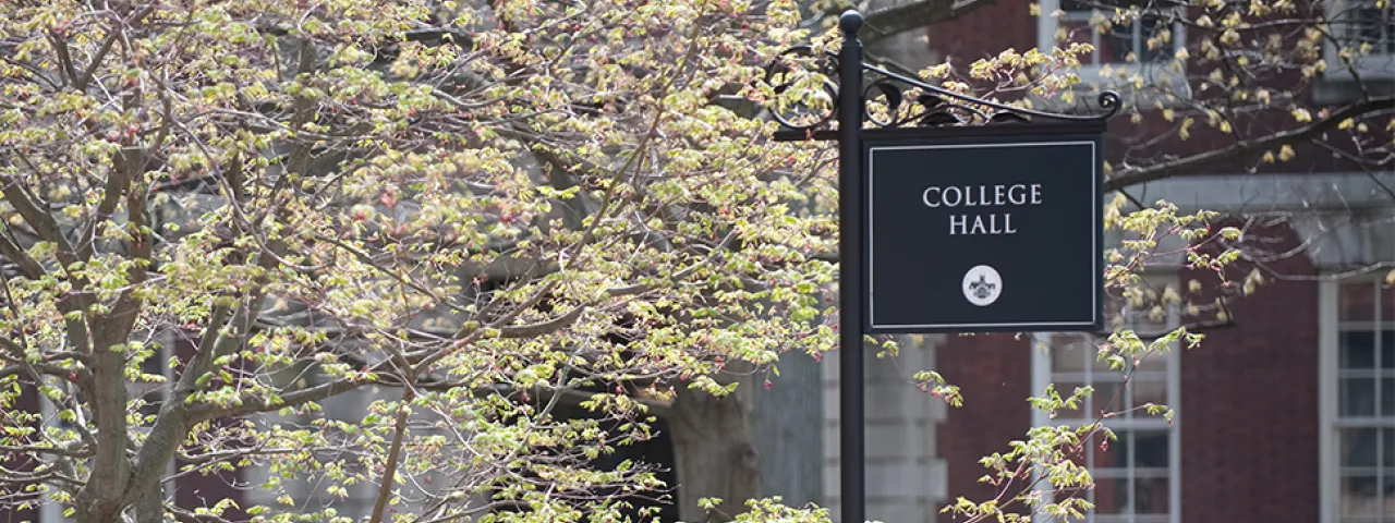 A sign reading College Hall is flanked by a tree in bloom