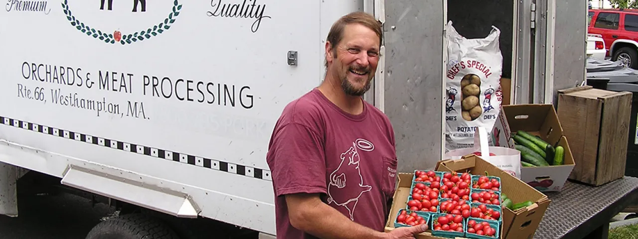 Man from local farm displays his fresh tomatoes from the back of a truck