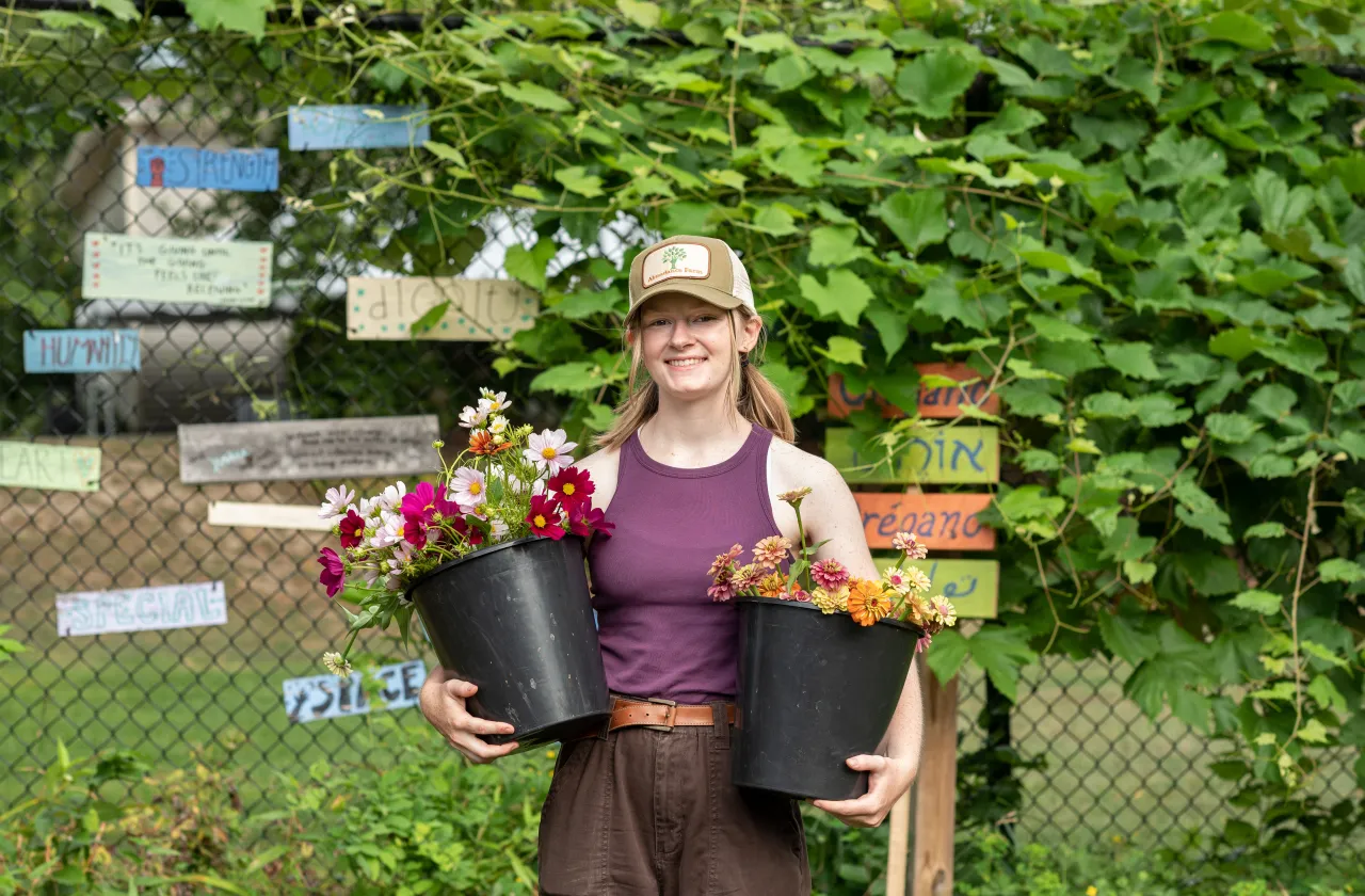 A student carrying two potted plants.