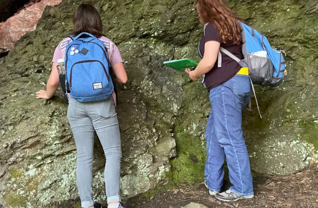 Two students inspecting rock surfaces.
