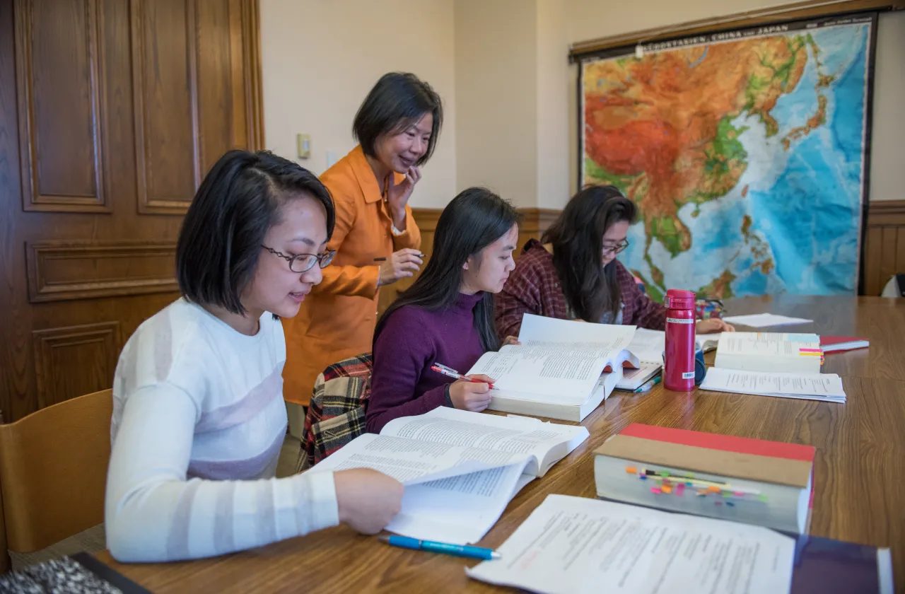 Professor Sujane Wu talks to three students in a class.