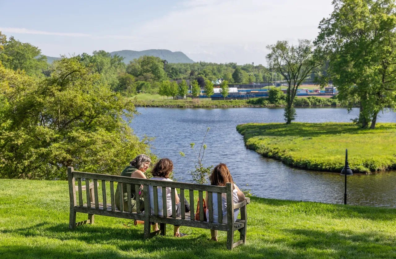 Alums sit on a bench looking out over Paradise Pond