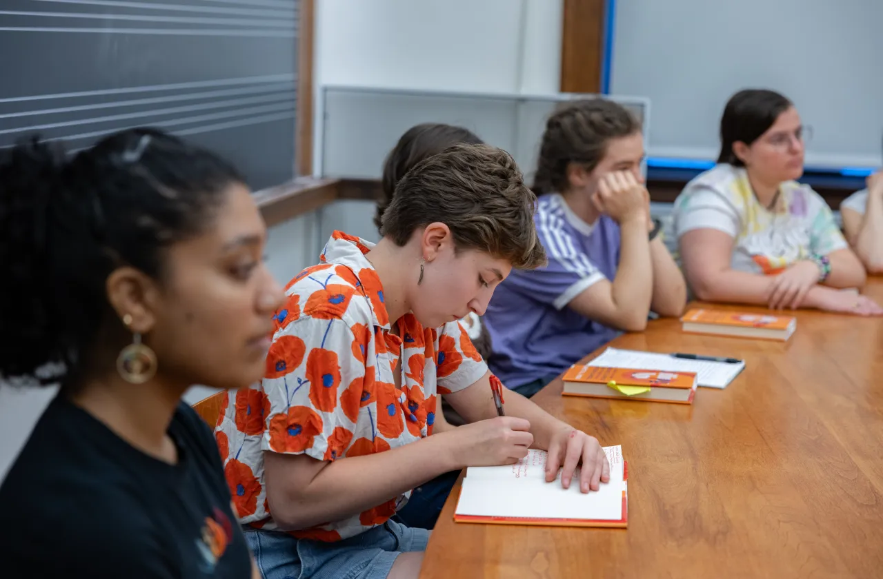 A student writing in a book during a discussion