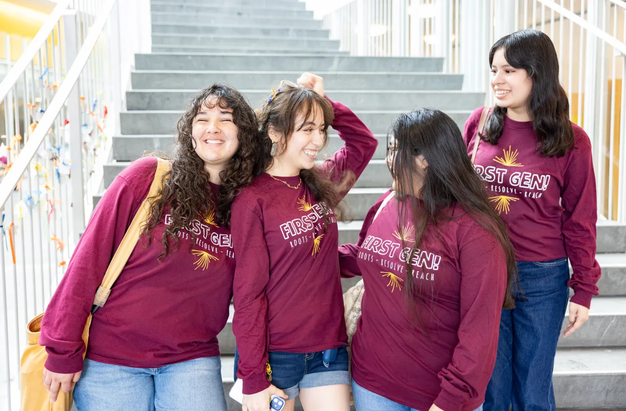 Four first-generation students in matching T-shirts on the steps of the Campus Center