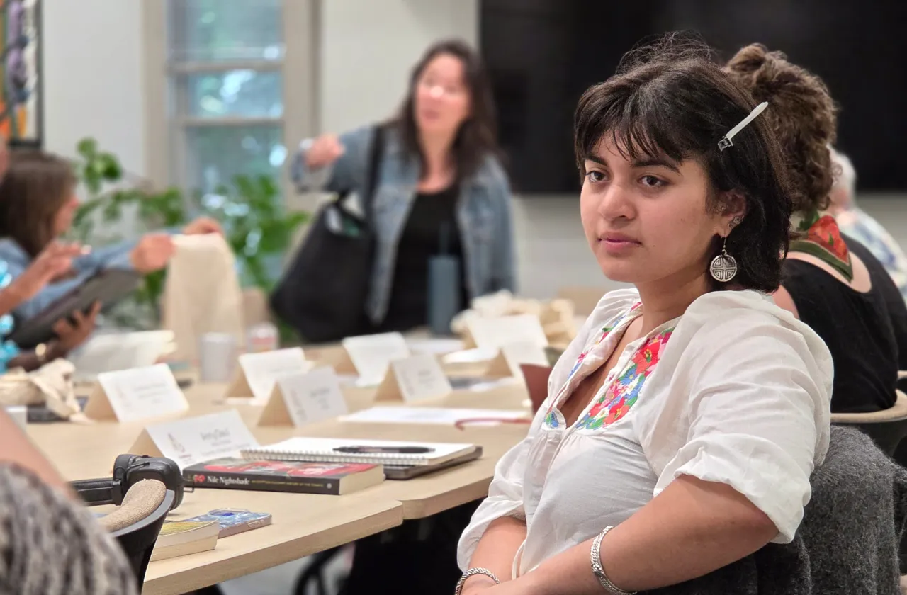 Dina Alam sitting attentively at a seminar table during a conference meeting.