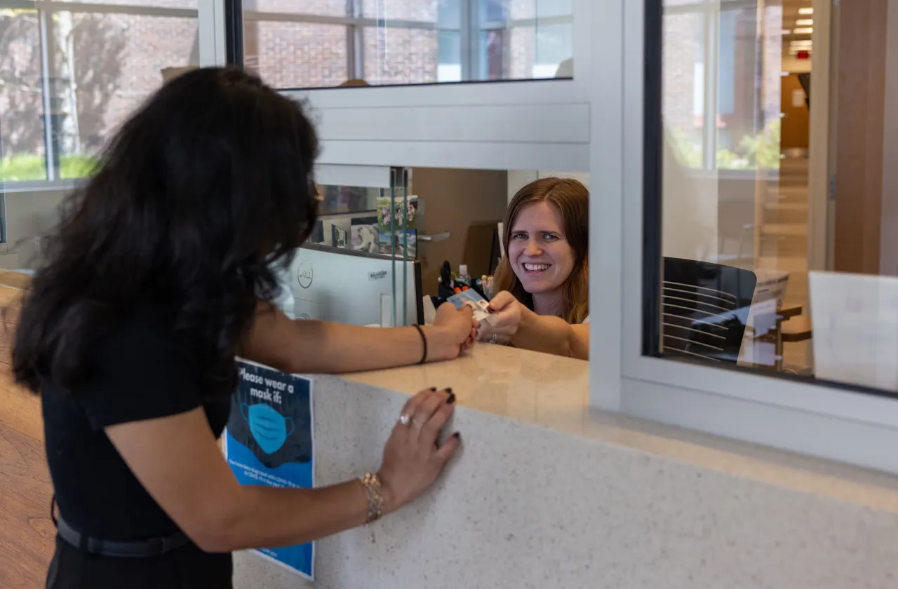 A receptionist at the Schacht Center hands a student a card