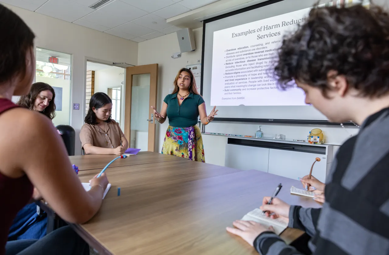 Someone gives a presentation on harm reduction to a group of students