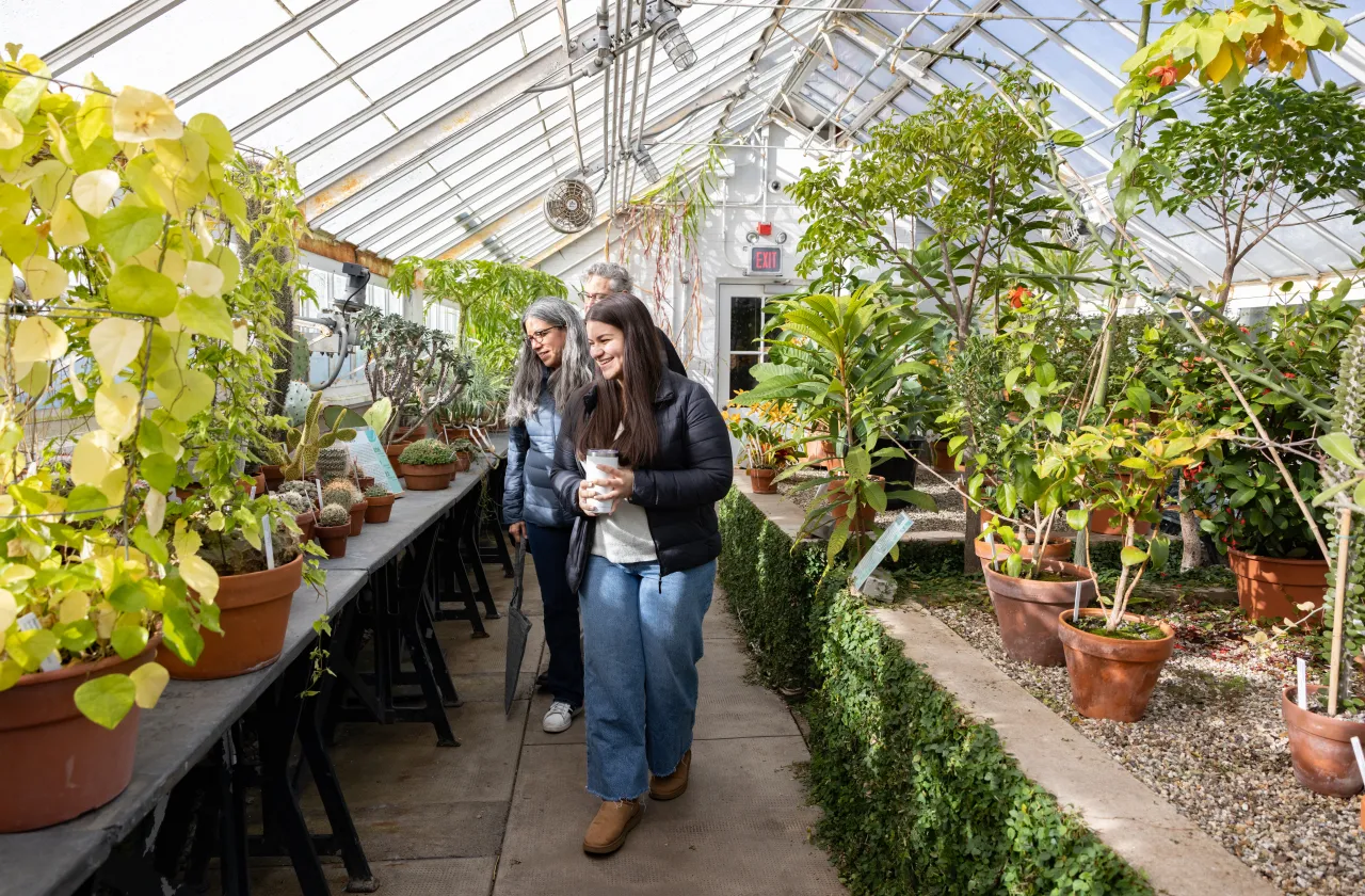 A student and parents walk through the greenhouses