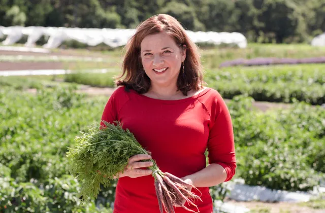 Amy Traverso holding a bunch of carrots outside at a nursery