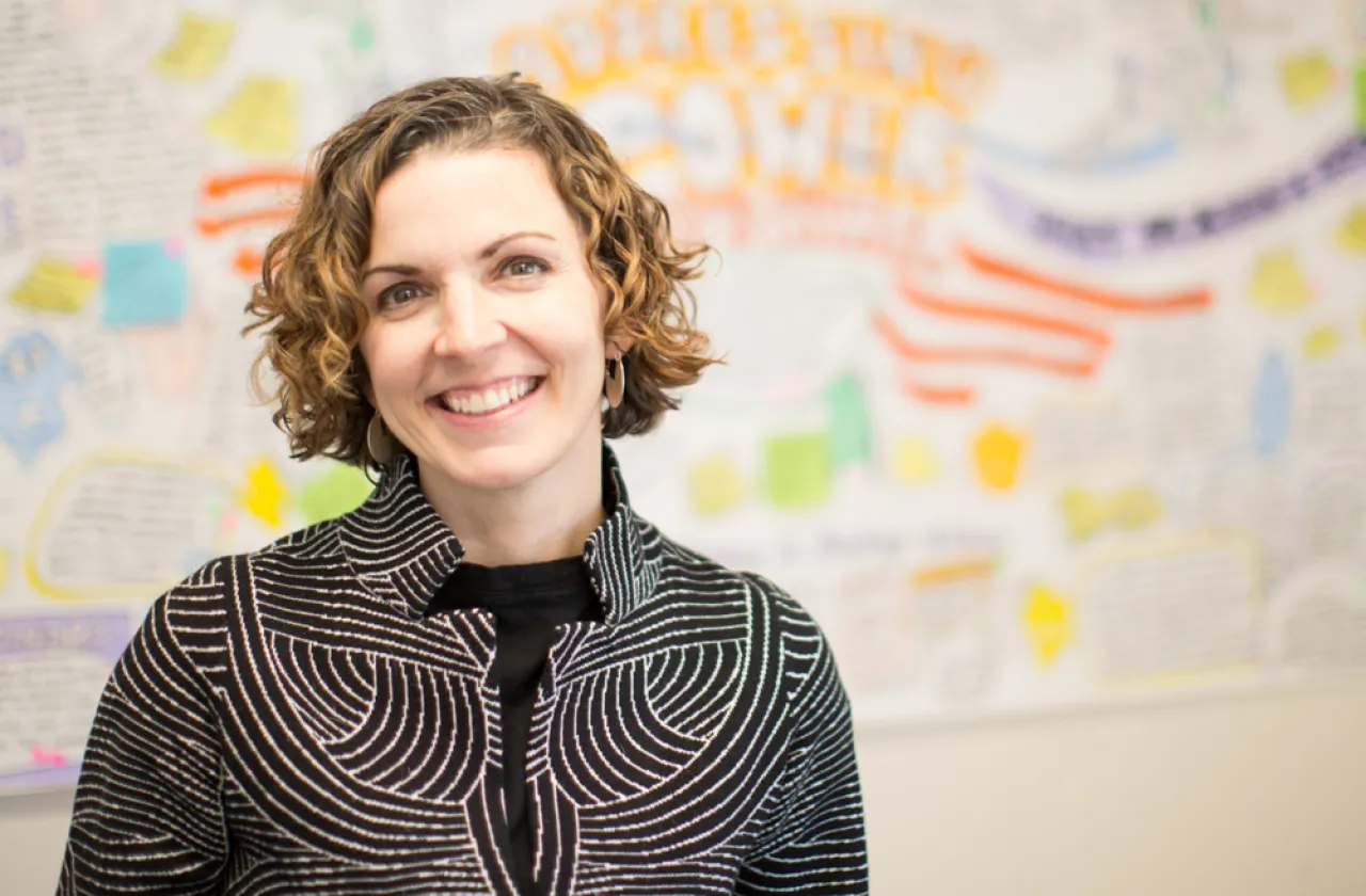 Erin Cohn against a out-of-focus white board covered with writing in bright marker