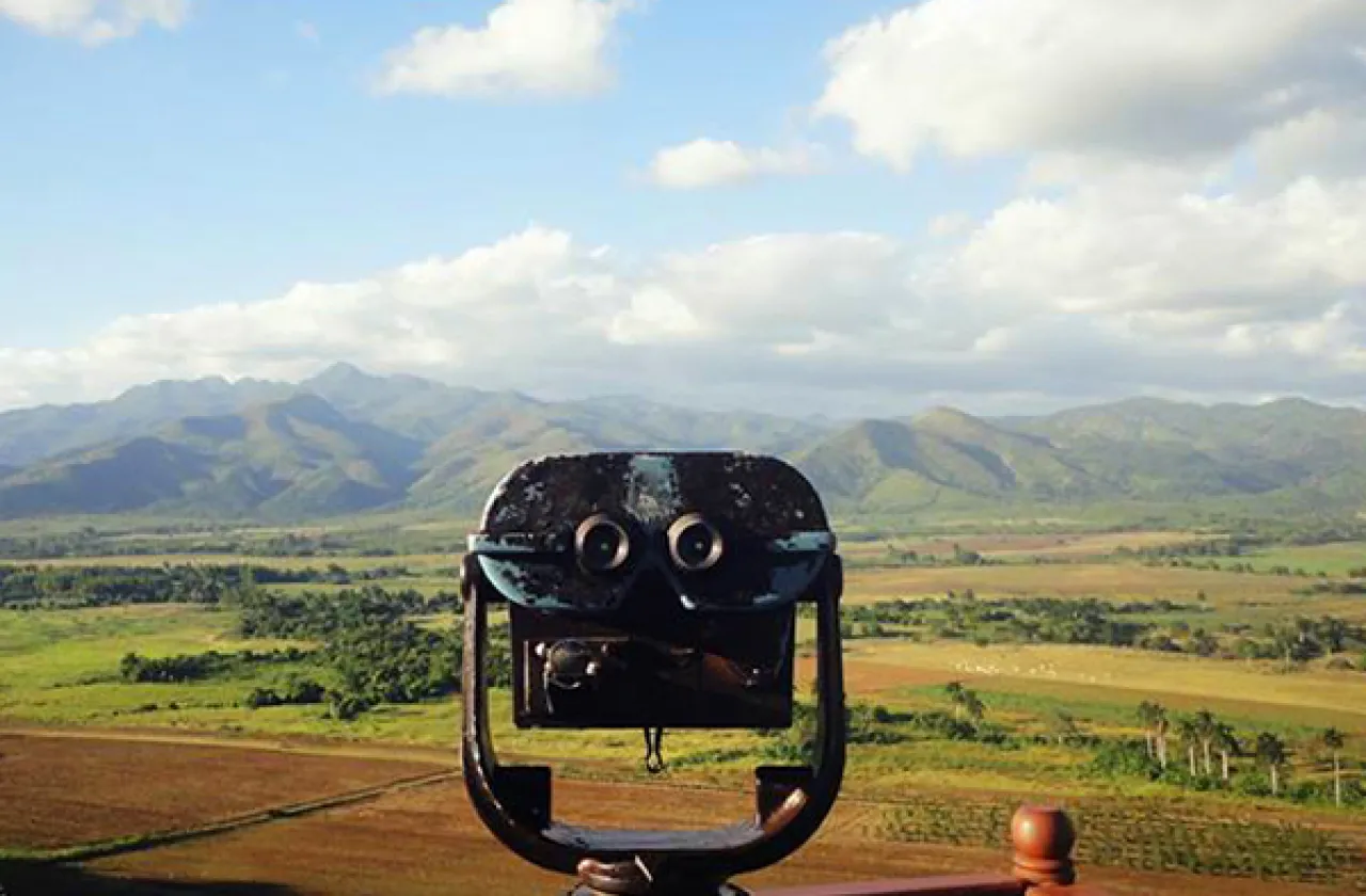 Viewfinder and panoramic view of a farm field, palm trees, and mountains