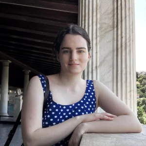  Emma Agudelo ‘24 with a blue top leaning against a wall with classical columns behind