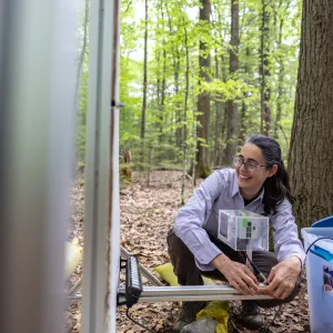 Professor Mariana Abarca poses near her moth monitoring device in a woodsy spot at MacLeish Field Station
