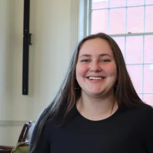 Headshot of Maggie Bohanek smiling brightly in a long-sleeved black top indoors.