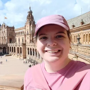 Nikolina Gvozdenovic taking a smiling selfie in front of the Plaza de España in Seville, Spain.