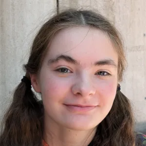 Headshot of Rachel Davison with hair in low pigtails, smiling gently against a plain background.