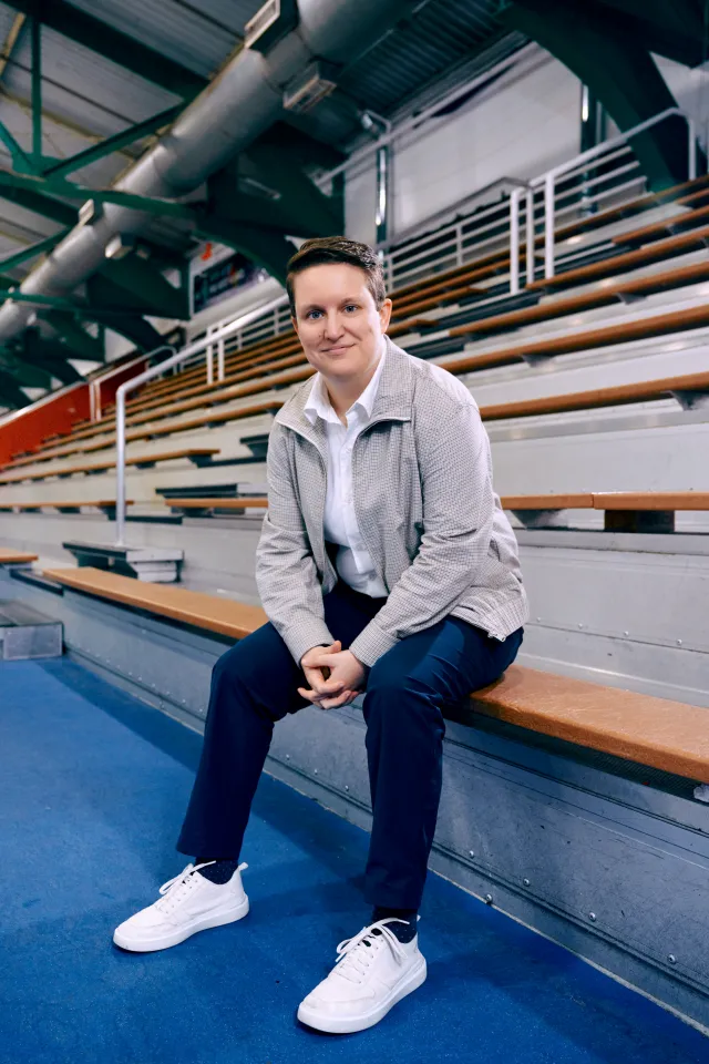 Nora Cothren sitting on the bleachers at an ice rink.