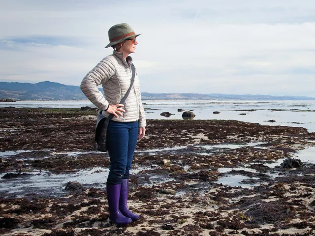 Mary Ellen Hannibal wearing purple boots in coastal wetlands looking toward the horizon