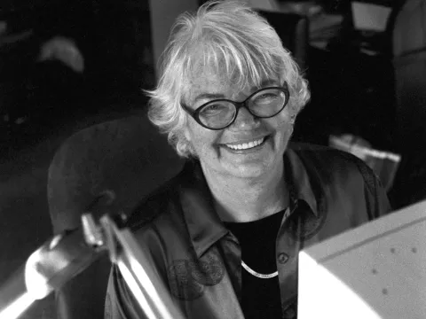 Molly Ivins smiling into the camera sitting at a computer