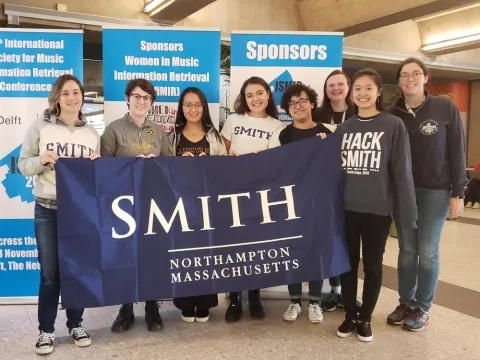 Group of students smiling at the camera holding Smith banner.