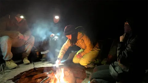 Students cook outdoors on backpacking stoves.