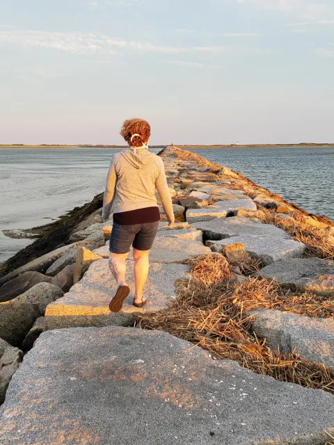 Person walking the causeway with mask strings in her curly hair