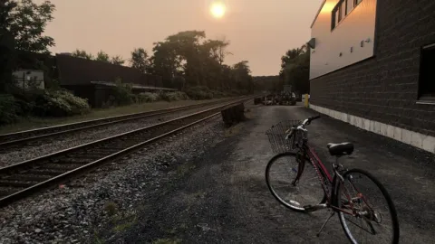 Bicycle near train tracks with sun setting by Liliana Wollheim Martinez